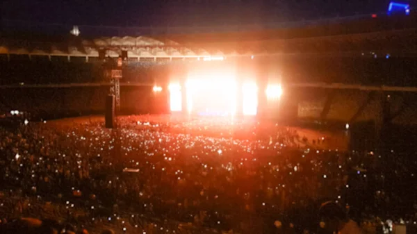 Foto borrosa abstracta de gran multitud en el concierto de rocas en el estadio por la noche. Fondo perfecto para ilustrar fiestas, discotecas o festivales de música —  Fotos de Stock