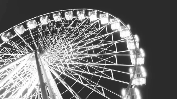 Black and white image of rotating illuminated ferris wheel in amusement park at night — Stock Photo, Image