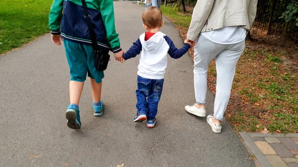 Foto de familia feliz con niño pequeño cogido de la mano y caminando en el parque — Foto de Stock