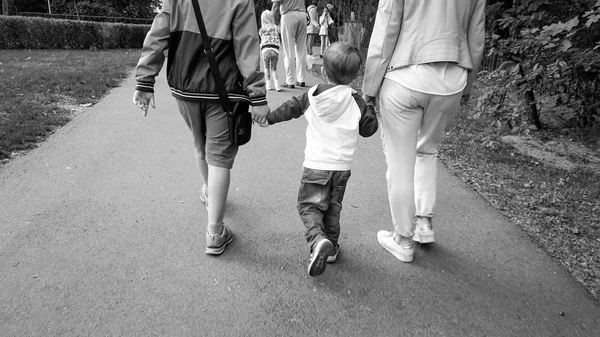 Black and white image of happy family holding by hands and walking in autumn park — Stock Photo, Image