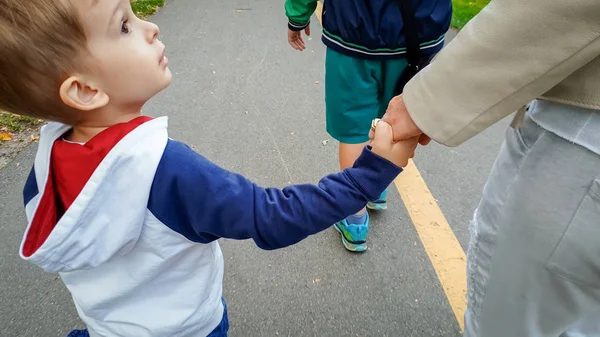Elleri ile tutarak ve parkta yürüyüş yürümeye yürümeye başlayan çocuk ile mutlu aile fotoğrafı — Stok fotoğraf