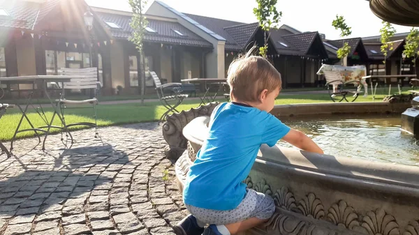 Portrait d'adorable garçon tout-petit de 3 ans touchant l'eau dans la fontaine au parc — Photo