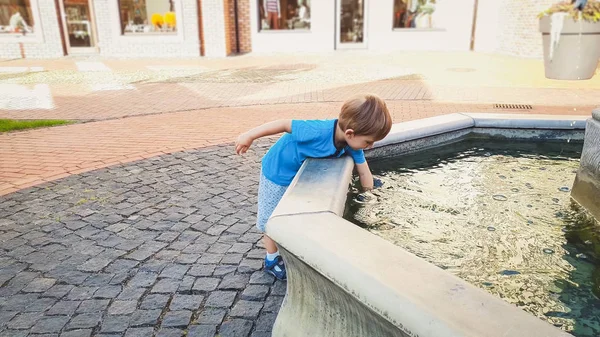 Portrait d'adorable garçon tout-petit de 3 ans touchant l'eau dans la fontaine au parc — Photo