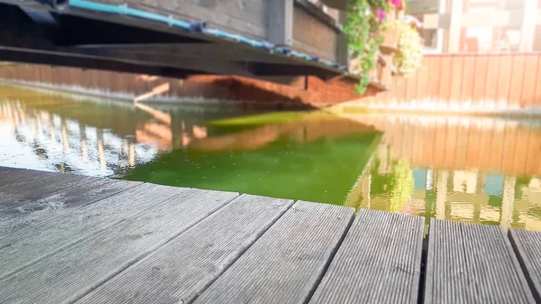 Immagine ravvicinata di vecchia tavola di legno o tavole contro il fiume calmo e ponte nella vecchia città europea. Ricevuto. Sfondo perfetto per inserire immagini, prodotti o oggetti — Foto Stock