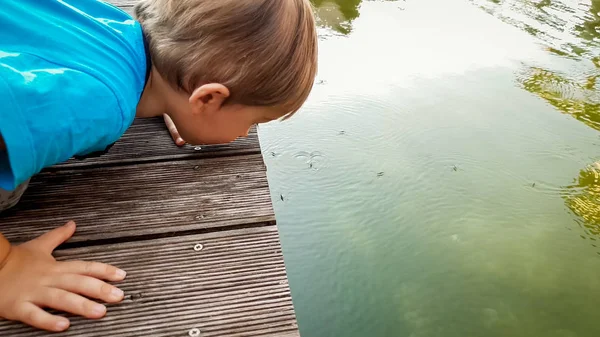 Portrait d'adorable tout-petit garçon regardant à la surface du lac et regardant beaucoup de strideuses flottantes — Photo
