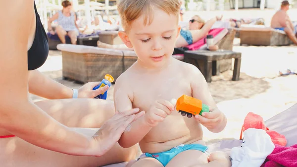 Zbliżenie portret szczęśliwej rodziny adorable 3 lat chłopiec chłopca relaks na plaży i stosowanie UV balsam ochrony przed słońcem na Trepka przed opalaniem — Zdjęcie stockowe