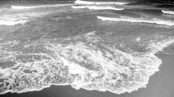 Чорно-біле зображення морських хвиль, що котиться на піщаному березі — стокове фото