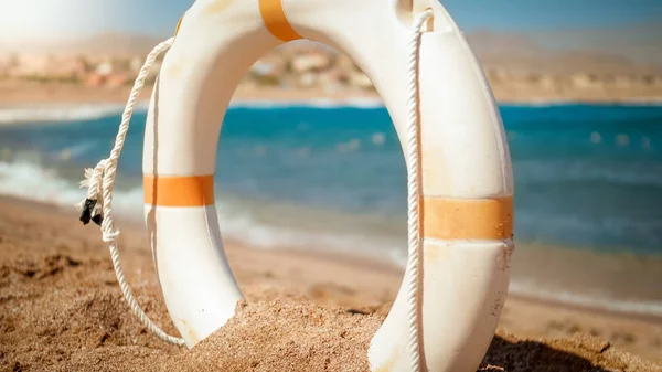 Εικόνα από λευκό πλαστικό δαχτυλίδι εξοικονόμησης ζωής στην παραλία της θάλασσας σε φωτεινή ηλιόλουστη μέρα. Τέλεια βολή για να απεικονίσει καλοκαιρινές διακοπές διακοπών στον ωκεανό. — Φωτογραφία Αρχείου