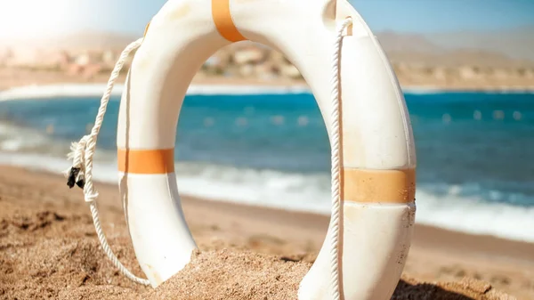 Hermosa imagen de anillo de ahorro de vida de plástico blanco de pie en la playa de arena del mar en el día soleado brillante. Tiro perfecto para ilustrar vacaciones de verano en el océano . —  Fotos de Stock