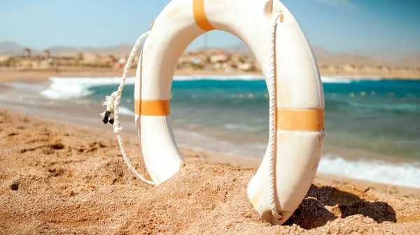 Hermosa imagen de anillo de ahorro de vida de plástico blanco de pie en la playa de arena del mar en el día soleado brillante. Tiro perfecto para ilustrar vacaciones de verano en el océano . —  Fotos de Stock