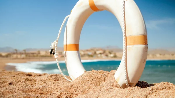 Imagen de primer plano del anillo salvavidas de plástico blanco en la playa del mar en un día soleado brillante. Tiro perfecto para ilustrar vacaciones de verano en el océano . —  Fotos de Stock