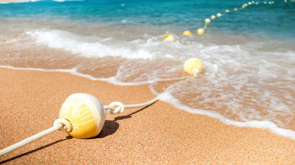 Imagen de primer plano de boyas flotantes de plástico conectadas en línea por una cuerda tendida en la playa del mar. Tiro perfecto para ilustrar vacaciones de verano en el océano . —  Fotos de Stock