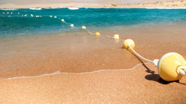 Κοντινά πλάνα από πλαστικά αιωρούμενα σημαδούρες που συνδέονται στη γραμμή με σχοινί που βρίσκεται στην παραλία της θάλασσας. Τέλεια βολή για να απεικονίσει καλοκαιρινές διακοπές διακοπών στον ωκεανό. — Φωτογραφία Αρχείου
