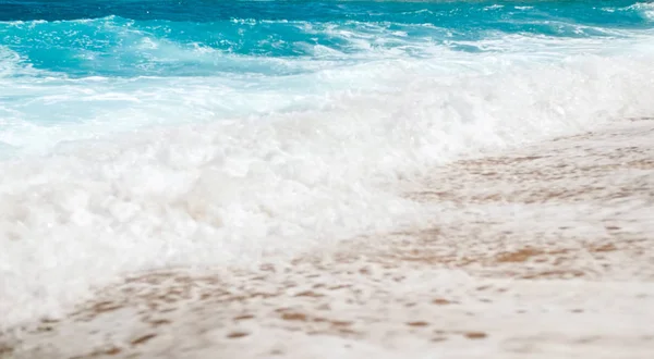 Красивое изображение бирюзовых морских волн, катящихся над берегом в яркий солнечный день — стоковое фото