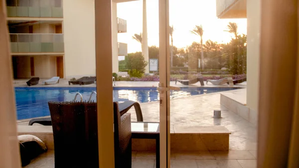 Bela vista de dentro da luxuosa villa em espreguiçadeiras e espreguiçadeiras na piscina e belo céu pôr do sol — Fotografia de Stock