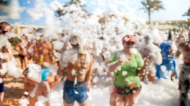 Yaz tatili tatilinde deniz plajında dans eden büyük kalabalığın bulanık görüntüsü. İnsanlar eğleniyor ve kutluyor.