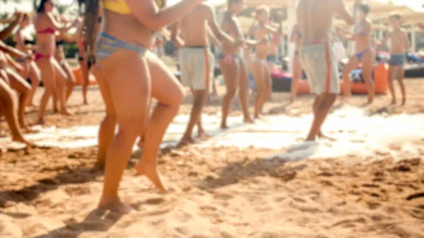 Defocused image of happy cheerful crowd having fun on the soap foam disco party on the sandy sea beach — Stock Photo, Image