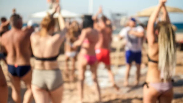 Blurred image of big crowd dancing on the sea beach on summer holiday vacation. People having fun and celebrating. — Stock Photo, Image