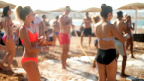 Imagen desenfocada de un gran grupo de personas bailando en la fiesta disco de la playa del mar. Personas que se divierten durante las vacaciones de verano —  Fotos de Stock