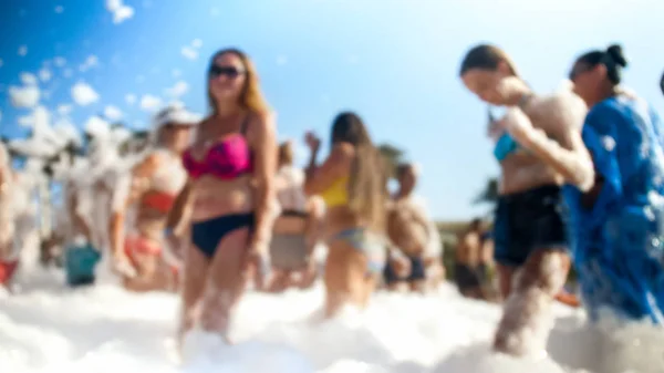 Foto borrosa de jóvenes amigos bailando en la fiesta disco de jabón en la playa del mar —  Fotos de Stock