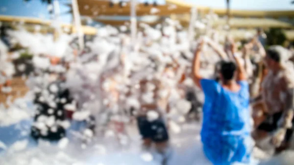 Defocused image of young people dancing on the sea beach at soap foam disco party. — Stock Photo, Image