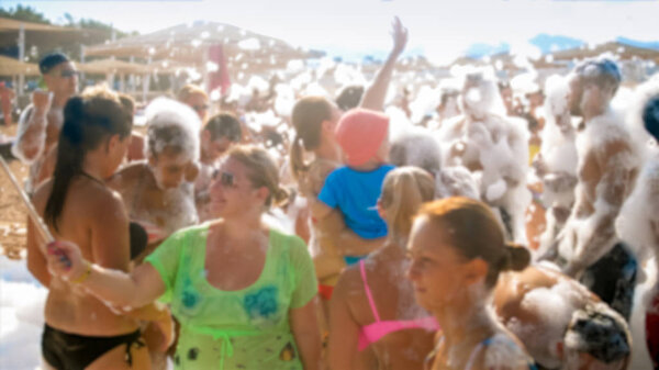 Ослабленное изображение большой группы людей, танцующих на пляжной дискотеке. Люди веселятся во время летних каникул
