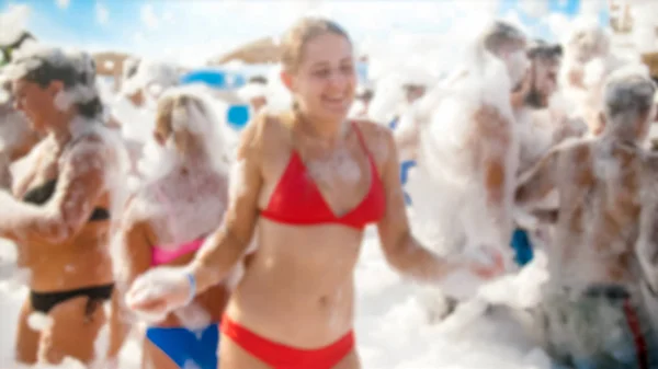 Portrait of happy laughing young woman in red bikini dancing on the sea beach. Girl having fun on sea beach soap foam disco party — Stock Photo, Image
