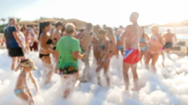 Defocused image of big group of people dancing on the sea beach disco party. People having fun during summer holiday vacation — Stock Photo, Image