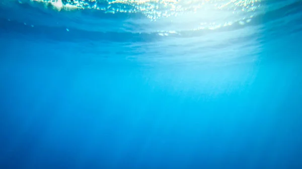 Erstaunliches Unterwasserbild von Sonne und Lichtstrahlen, die durch die Wasseroberfläche des tiefen Ozeans scheinen — Stockfoto