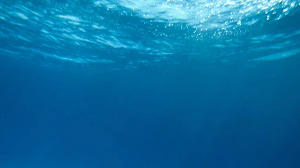 Imagem subaquática incrível de sol e raios de luz brilhando através da superfície profunda da água do oceano — Fotografia de Stock