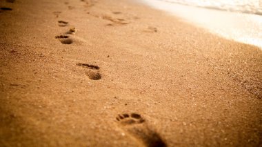 Gün batımı gökyüzüne karşı ıslak kumlu deniz plajında ayak izleri Closeup görüntü