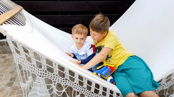 Porträt eines kleinen Jungen mit seinem älteren Bruder, der in der Hängematte im Hinterhof seines Hauses liegt — Stockfoto