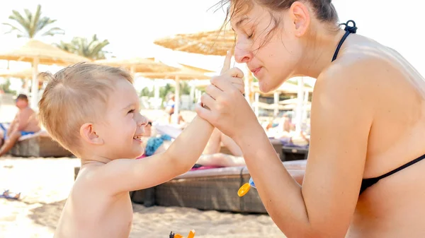 Zbliżenie portret szczęśliwej rodziny adorable 3 lat chłopiec chłopca relaks na plaży i stosowanie UV balsam ochrony przed słońcem na Trepka przed opalaniem — Zdjęcie stockowe