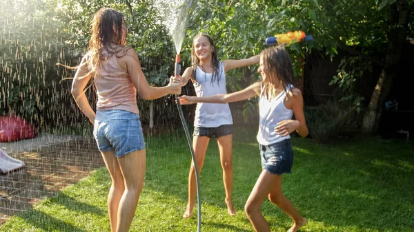 Foto van drie vrolijke tiener meisjes dansen in de achtertuin tuin udner tuin water slang — Stockfoto