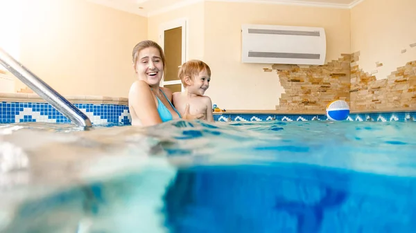 Porträt eines glücklich lächelnden Kleinkindes, das mit seiner Mutter im Pool Schwimmen lernt. Familie mit Spaß und Entspannung im Schwimmbad — Stockfoto