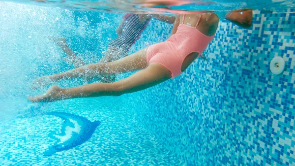 Underwater image of two teenage girls diving and swimming underwater at swimming pool — Stock Photo, Image