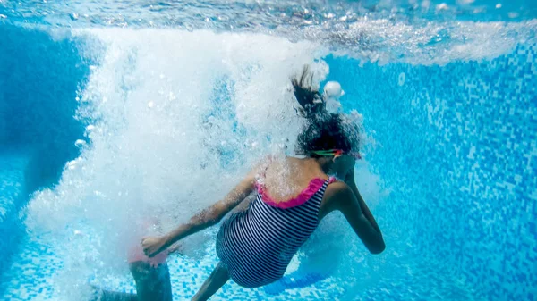 Imagen submarina de dos adolescentes saltando y buceando en la piscina en el gimnasio —  Fotos de Stock