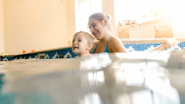 Porträtt av Happy leende barn pojke lärande simning med mor i poolen. Familj ha kul och koppla av i poolen — Stockfoto