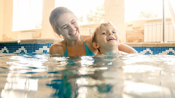 Porträt eines fröhlichen, jungen Motten mit einem dreijährigen Kleinkind, das im Pool des Hauses spielt. Kind lernt Schwimmen mit Eltern. Familie hat Spaß im Sommer — Stockfoto