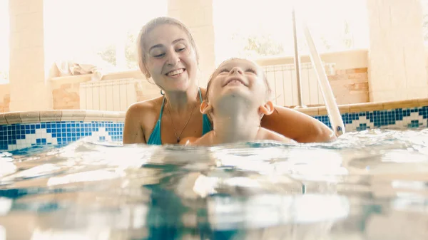 Kapalı havuzda yüzen genç anne ile 3 yaşındaki bebek çocuk portresi. Çocuk yüzme ve spor öğrenme. Aile zevk ve suda eğlenmek — Stok fotoğraf