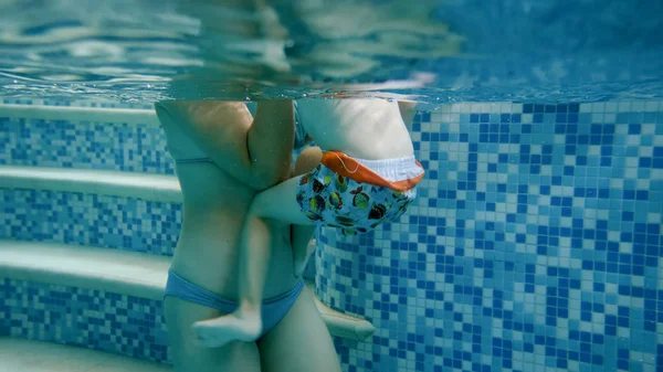 Imagen submarina de la joven madre enseñando a su niño de 3 años nadando en la piscina — Foto de Stock