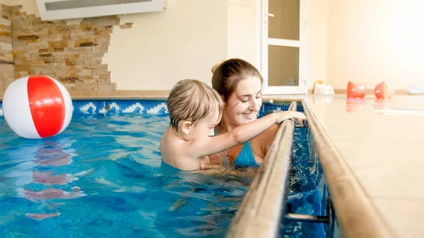 Spor salonunda havuzda yüzen 3 yaşındaki küçük oğlu ile mutlu gülümseyen anne portresi. Aile raelaxing, eğlenmek ve suda oynarken — Stok fotoğraf