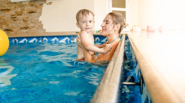 Porträt eines fröhlichen, jungen Motten mit einem dreijährigen Kleinkind, das im Pool des Hauses spielt. Kind lernt Schwimmen mit Eltern. Familie hat Spaß im Sommer — Stockfoto