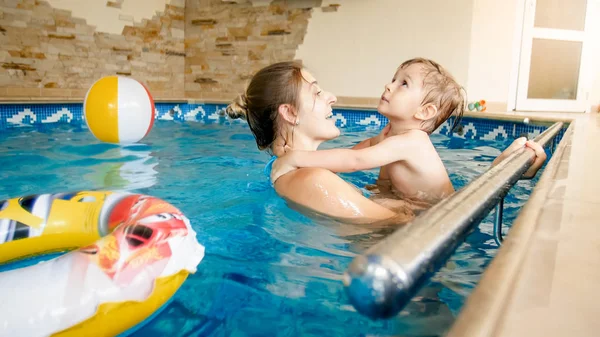 Porträt eines fröhlichen, jungen Motten mit einem dreijährigen Kleinkind, das im Pool des Hauses spielt. Kind lernt Schwimmen mit Eltern. Familie hat Spaß im Sommer — Stockfoto