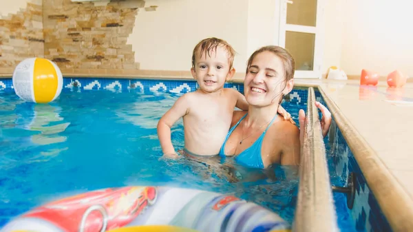 Retrato de niño sonriente feliz jugando con la bola de playa colorida inflable con la madre en la piscina interior — Foto de Stock