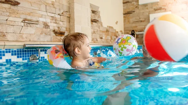 Retrato de niño riendo feliz con madre joven jugando con la bola inflable colorida de la playa en la piscina en el complejo del hotel del verano — Foto de Stock