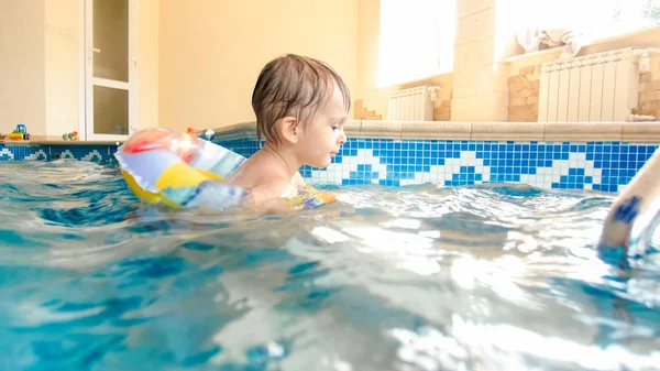 Portret van lachen en glimlachen 3 jaar oude kleine jongen zwemmen met opblaasbare kleurrijke ring en spelen met strandbal in zwembad — Stockfoto