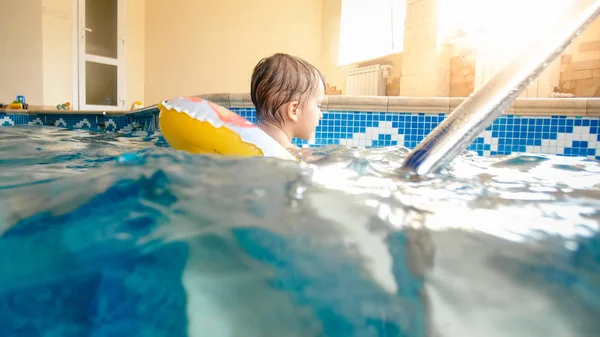 Porträt eines fröhlichen Kleinkindes, das mit aufblasbarem Beachball und buntem Ring im Hallenbad im Haus spielt — Stockfoto