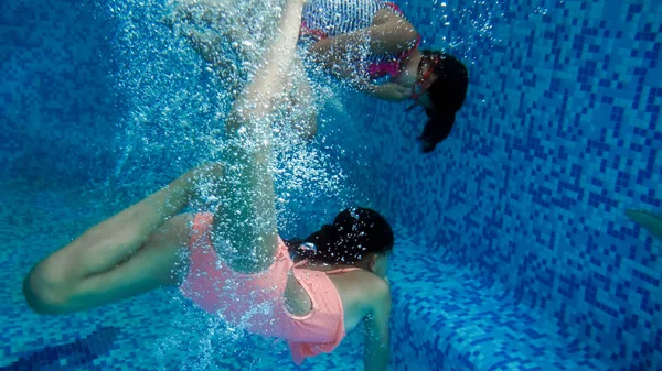 Podwodne wizerunek dwóch nastoletnich dziewcząt skoki w basenie w letnim hotelu Resort — Zdjęcie stockowe