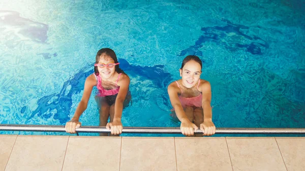 Retrato de dos amigas adolescentes nadando y divirtiéndose en la piscina interior —  Fotos de Stock